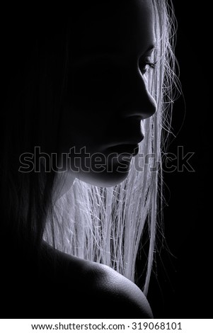 sad female profile silhouette in dark, toned image