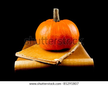 Studio shot of large halloween pumpkin with two old books on black background.