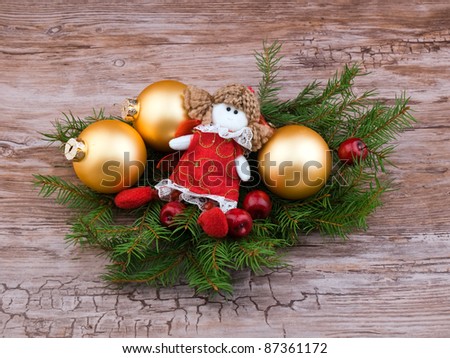 Golden christmas ball and little angel figurine with fresh spruce branch on old wooden background