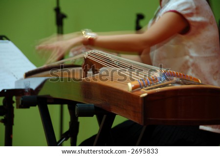 a musician playing  gu-jeng, an string musical instrument with  double string and flet