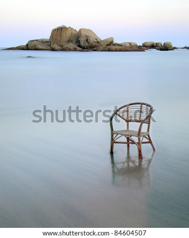A long exposure beach with rattan chair. chair face to left side. chair position at bottom right.