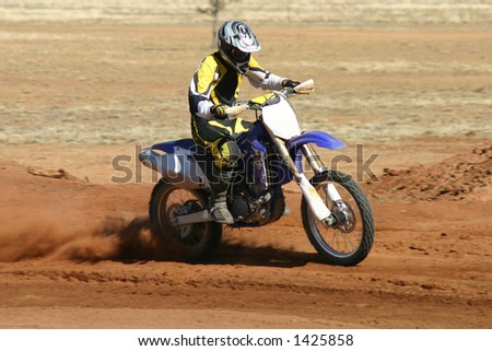 Removed all logos and numbers in this action shot of a motorbike taking a wide turn in a desert motor race.