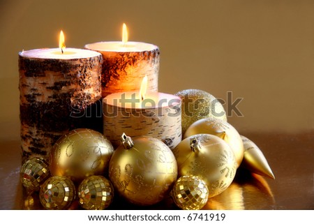 Golden Glow: A trio of candles glows warmly amongst glittering gold ornaments against a reflective gold background. Space for copy. Holiday concept.