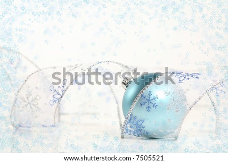 Snowflake Swirl: An frosty blue ornament lies in a spiral of transparent, glittery snowflake ribbon against a white background surrounded by snowflakes. Holiday concept.