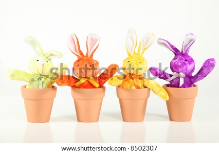 Colorful bunnies sprout from terra-cotta pots against a white background. Easter/spring concept.