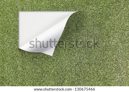 An artificial green grass turf surface peeling off at the edge with blank space for text.