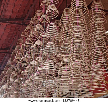 Spiral incense joss sticks hanging from a temple ceiling.