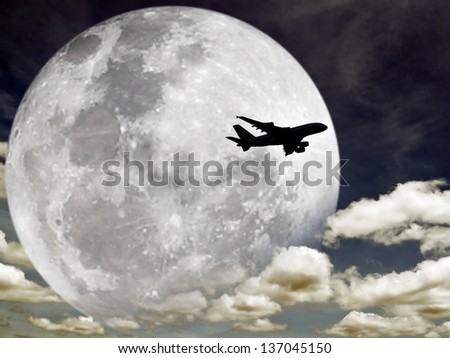 Silhouette of an airplane flying across a full moon on a cloudy night sky. Elements of this image furnished by NASA.