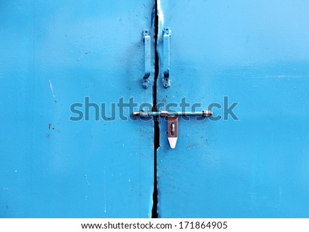A metal latch on a blank blue metal door panel.