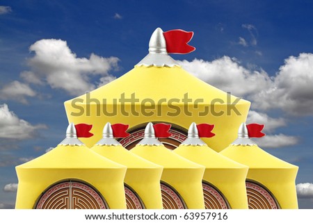 A happy image of a group of yellow castle top with red flag flying against a blue cloudy sky.