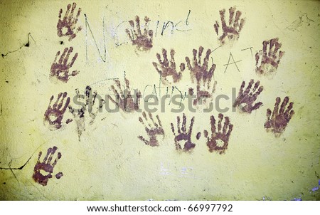 Grungy image of muddy hand print graffiti on a rustic wall.