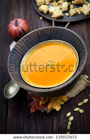 Vegetarian food concept. Pumpkin soup with pumpkin seeds, croutons and garnish on wooden background. Thanksgiving dinner