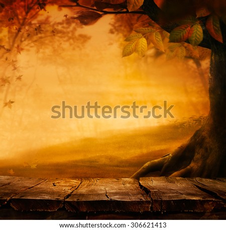 Wooden table. Autumn design with leaves falling in  forest and empty display. Space for your montage. Season fall background
