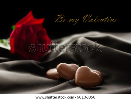 Chocolate hearts on fabric with red rose. Available space for your text.