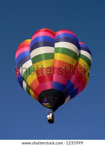 Bright colorful hot air balloon taking off into a clear blue sky
