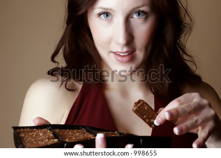 Red hair female holding a piece and a box of chocolate