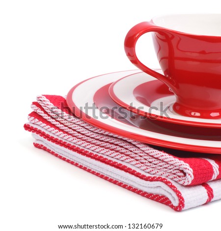 Beautiful red tea cup and saucer on a striped napkin folded isolated on white background