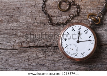 old gold pocket watch on a chain on an old wooden table close up