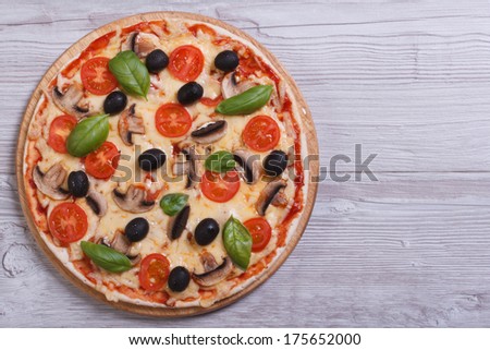 Mushroom pizza with olives, tomatoes and basil on the table. top view