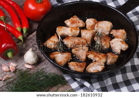 Pieces of grilled meat in a pan and vegetables on the table. view from above. horizontal