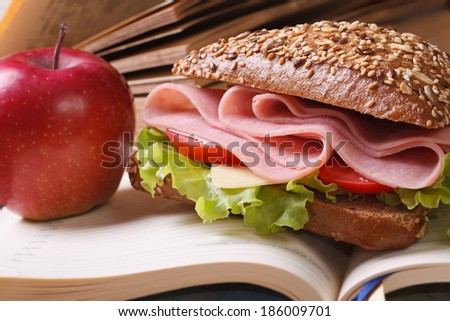 School lunch: a ham sandwich and an apple on open notebook close-up. horizontal