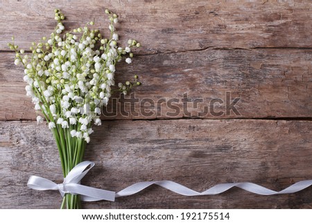 Beautiful floral frame with lilies of the valley flowers on old wooden table. horizontal