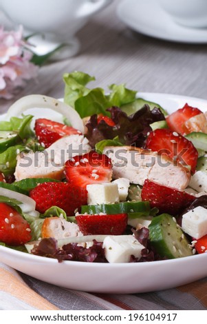 Tasty salad of strawberries with chicken and vegetables close-up. vertical