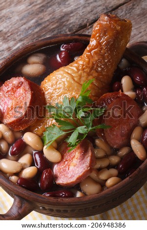 red and white beans with chicken legs and sausages in a bowl on the table. close up vertical