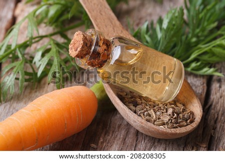 Useful carrot seed oil in glass bottle on the table close-up horizontal.