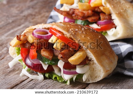 two doner kebab with meat, vegetables and fries in pita bread close-up on a napkin horizontal