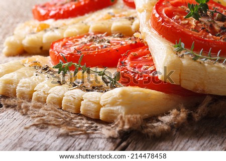 Puff pie with tomato, cheese and herbs on the table macro. horizontal