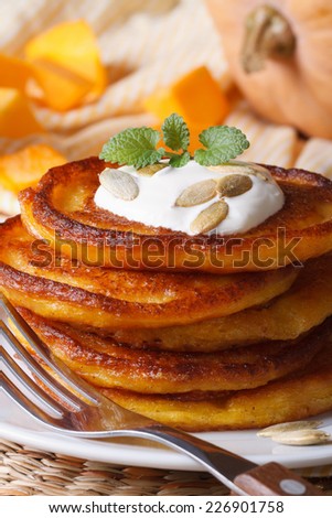 yellow pumpkin pancakes with sour cream and mint seeds macro. vertical