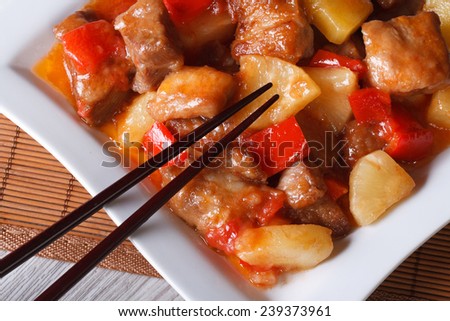 pork meat with pineapple and vegetables in sweet and sour sauce on a plate macro. horizontal view from above