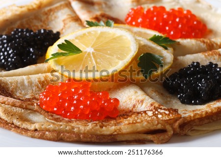 Thin pancakes with red and black caviar on a plate macro horizontal