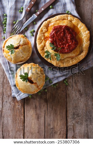 Australian meat pie on a wooden table. vertical view above, rustic style