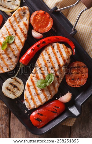 Chicken breast with tomatoes and peppers on the grill pan closeup.vertical view from above