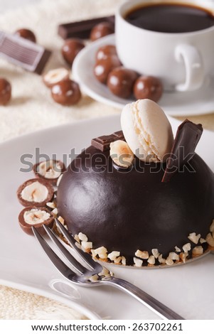 Round chocolate cake with nuts on a plate close-up and coffee on the table. vertical