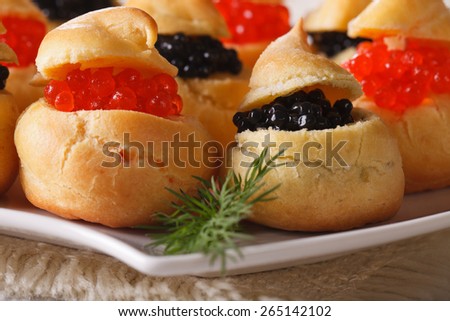 Fresh profiteroles with red and black caviar on a plate macro. horizontal