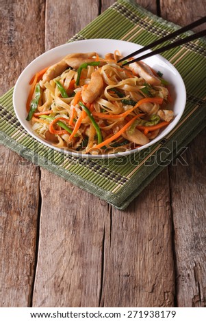 Chow mein with chicken and vegetables on the table. vertical