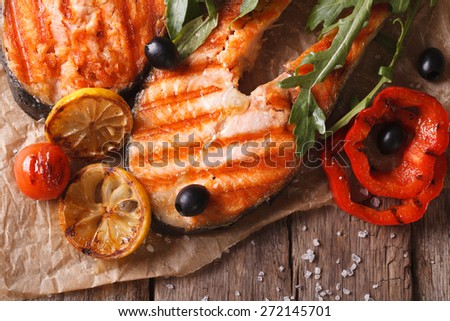 Grilled salmon steak and vegetables on paper. horizontal top view close-up, rustic style
