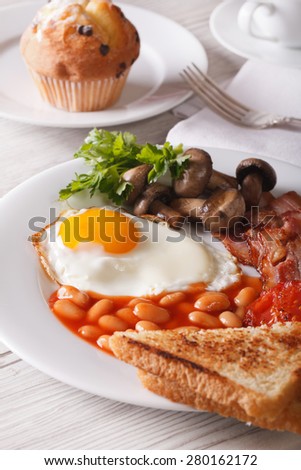A hearty English breakfast: fried eggs with bacon and vegetables close-up on a plate. Vertical