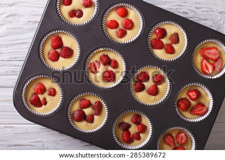 Preparation strawberry muffins in baking dish closeup. horizontal view from above