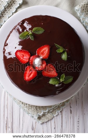 Fresh chocolate cake with strawberries on a table close-up. vertical top view