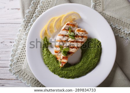 Grilled chicken and a side dish of green peas close-up on a white plate. horizontal view from above