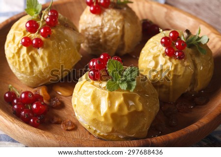 baked apples with honey decorated with fresh red currants and mint close up on a wooden plate. horizontal