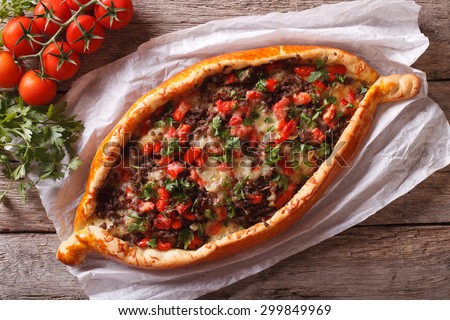 Turkish pide pizza with meat and vegetables close-up on the table. horizontal view from above