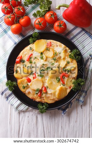 Delicious Spanish tortilla on a black frying pan close-up. vertical top view