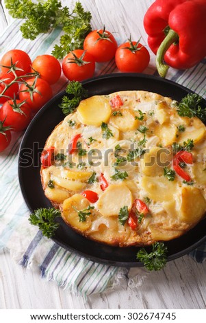 Delicious Spanish tortilla on a black frying pan close-up. vertical