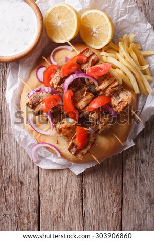 Greek souvlaki kebabs with vegetables and french fries on pita bread on the table. vertical top view
