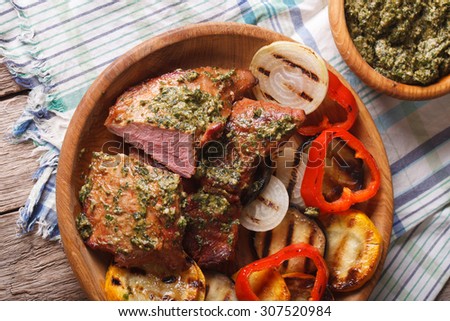 Veal meat and grilled vegetables with pesto sauce close-up on a plate. horizontal view from above